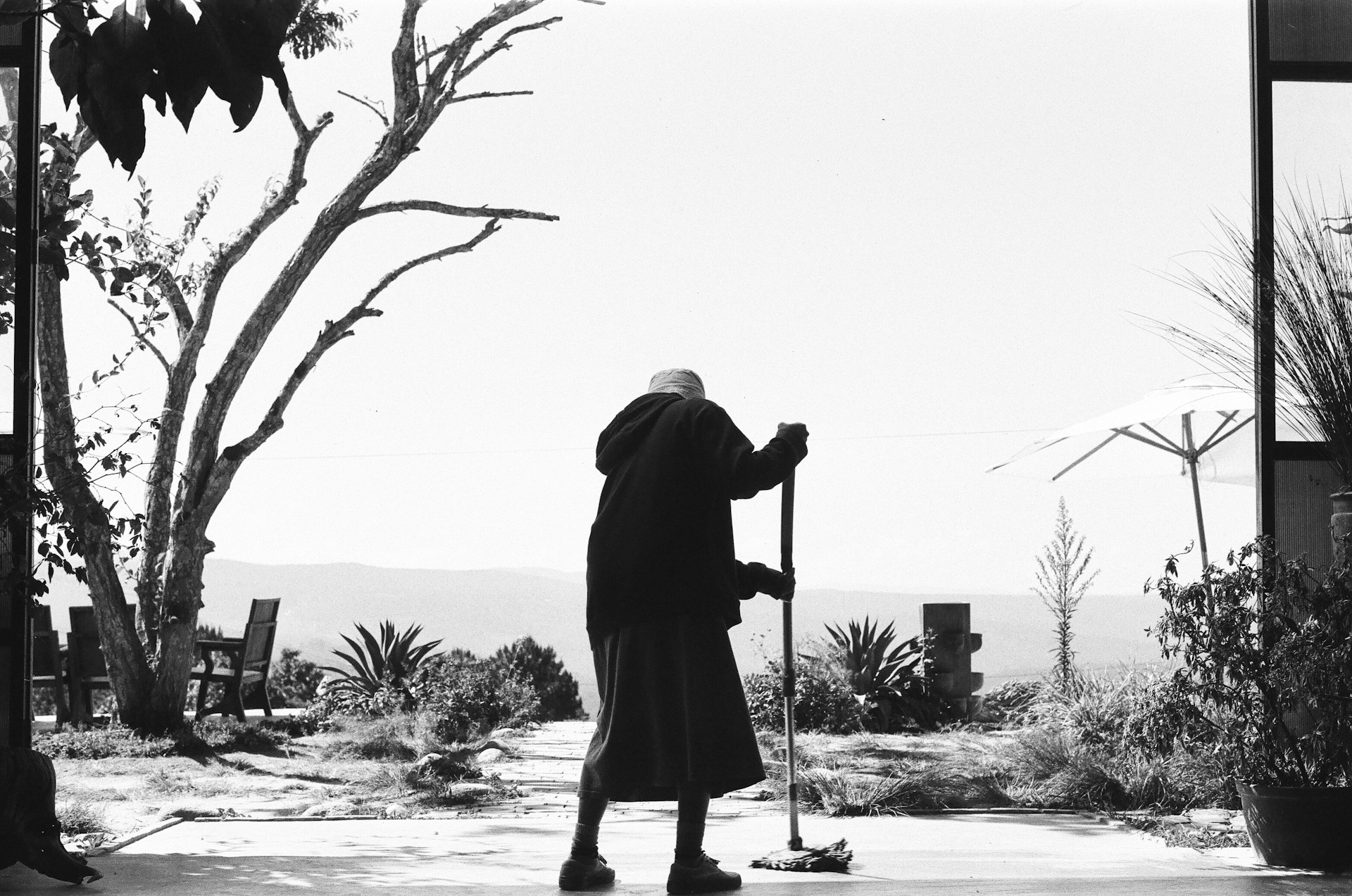A black-and-white shot of an older woman cleaning the floor | Source: Unsplash